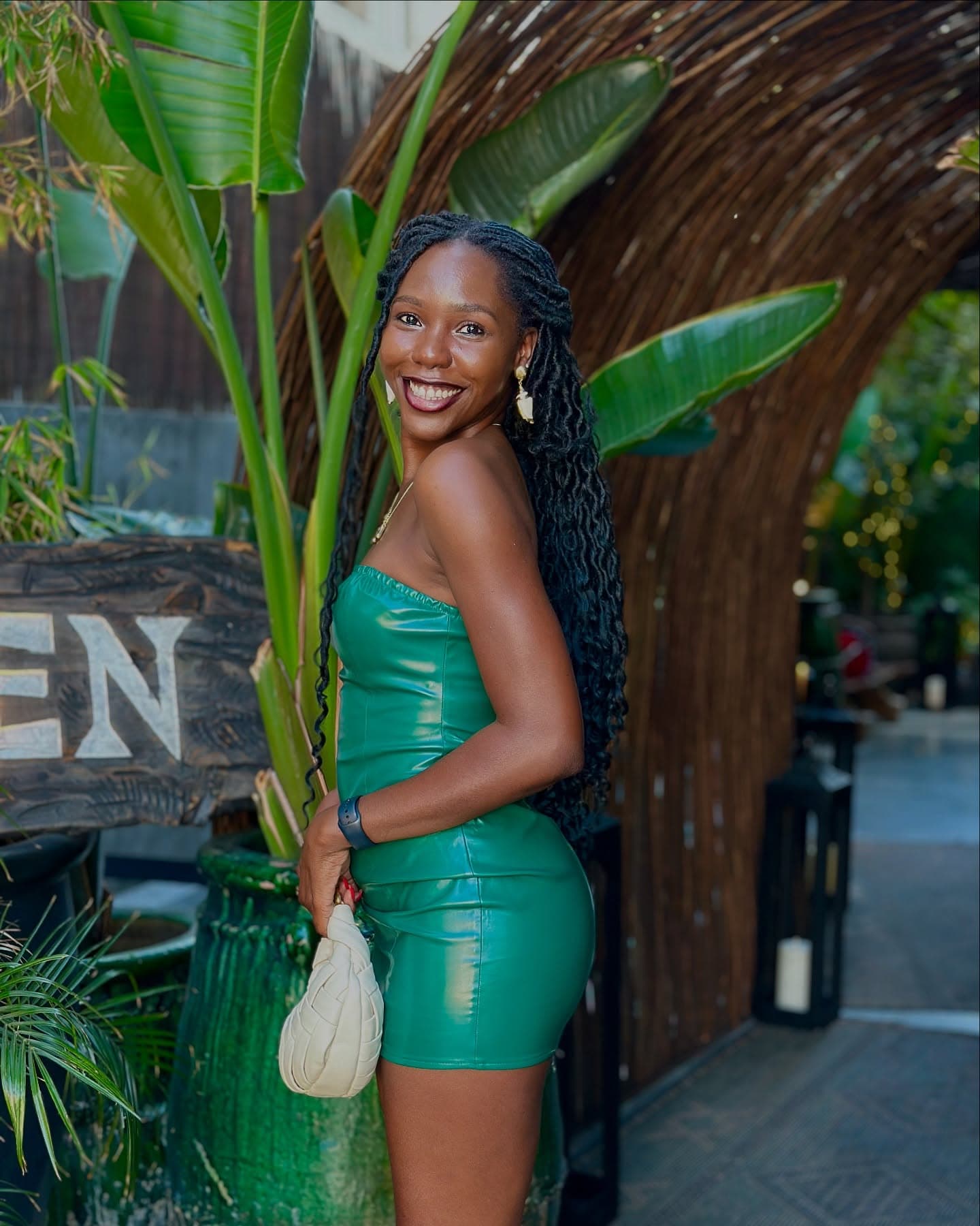 Smiling in a green leather dress at a tropical restaurant