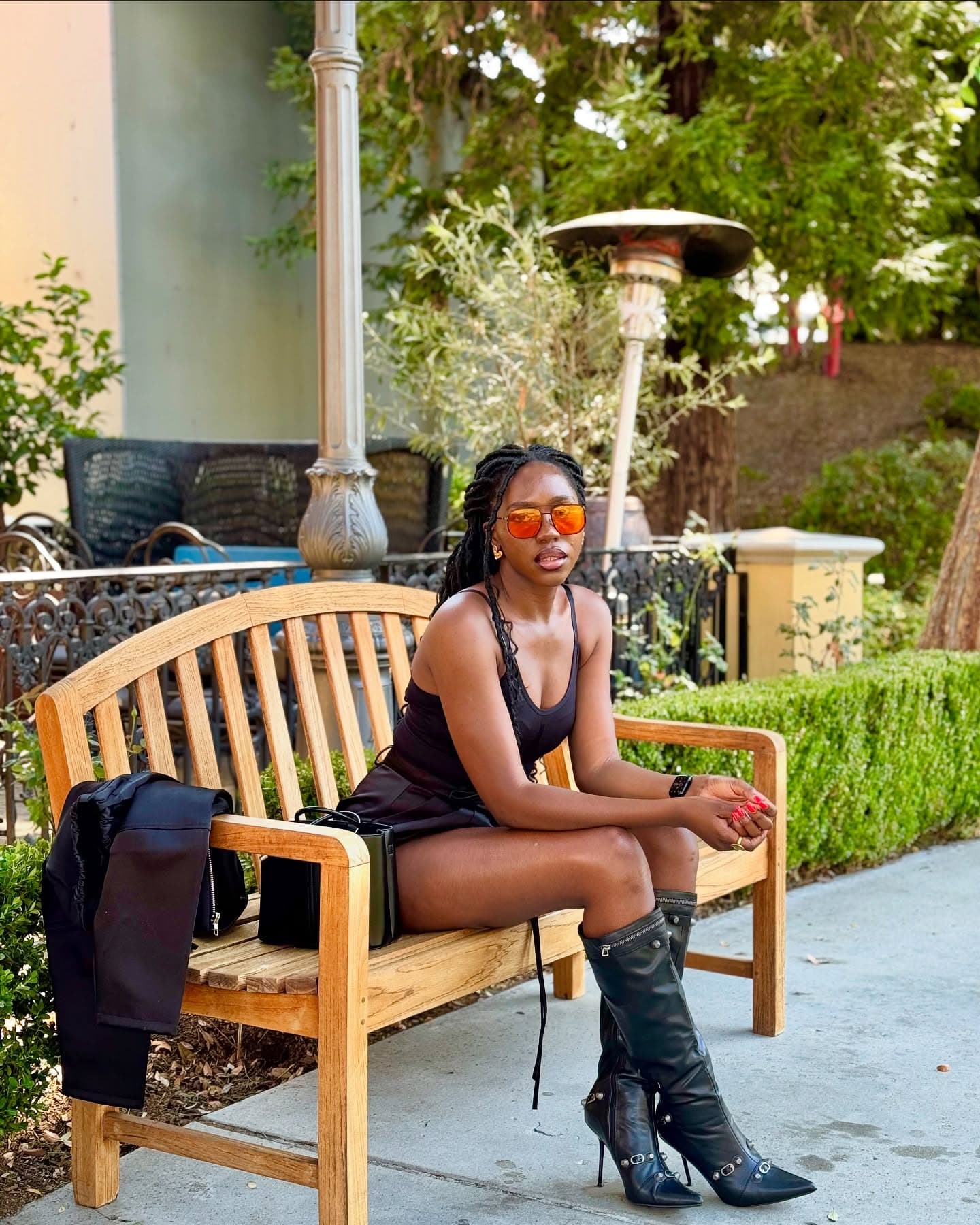Sitting on a garden bench in a black mini dress