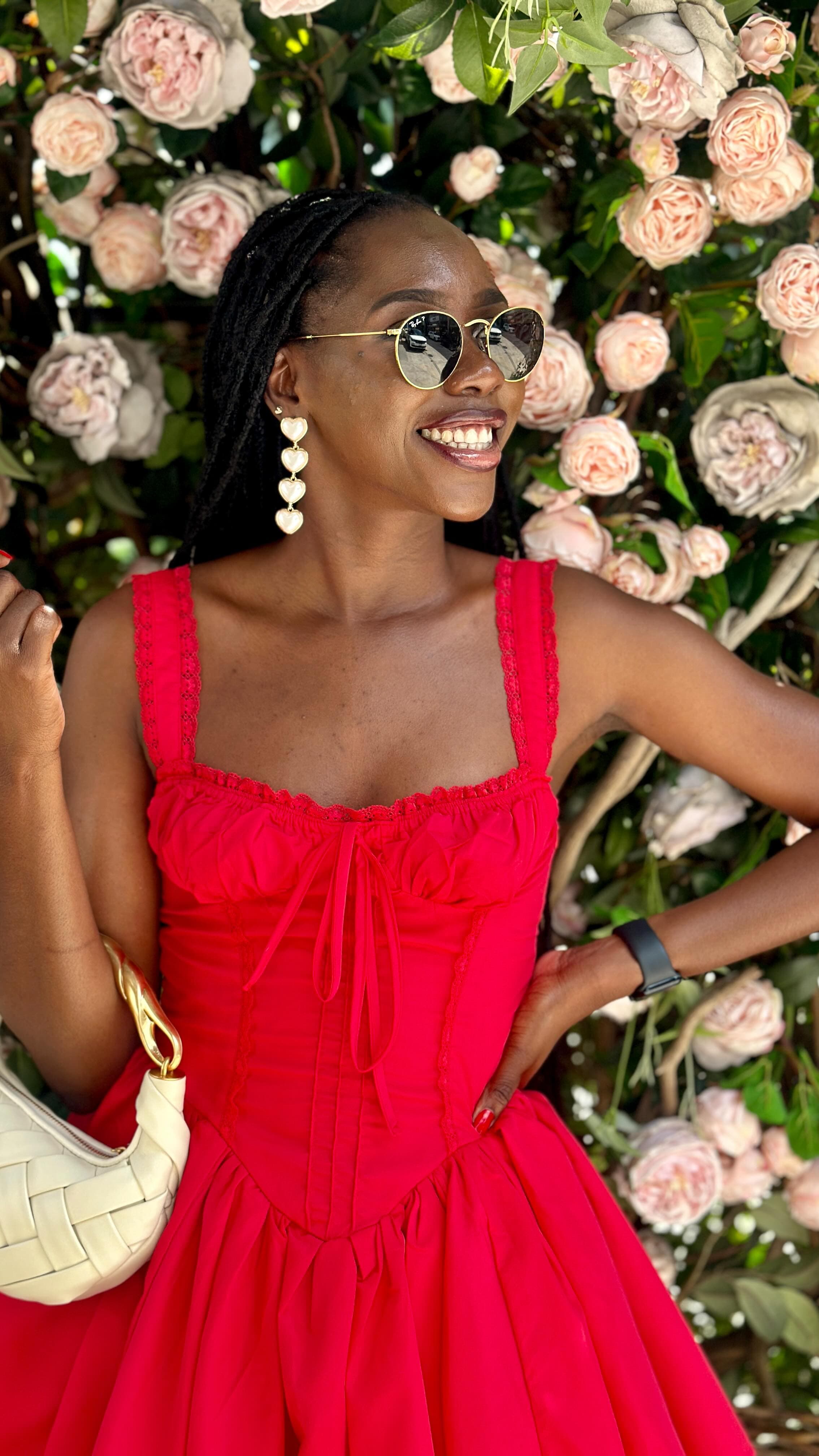 Red dress in front of a wall of pink roses