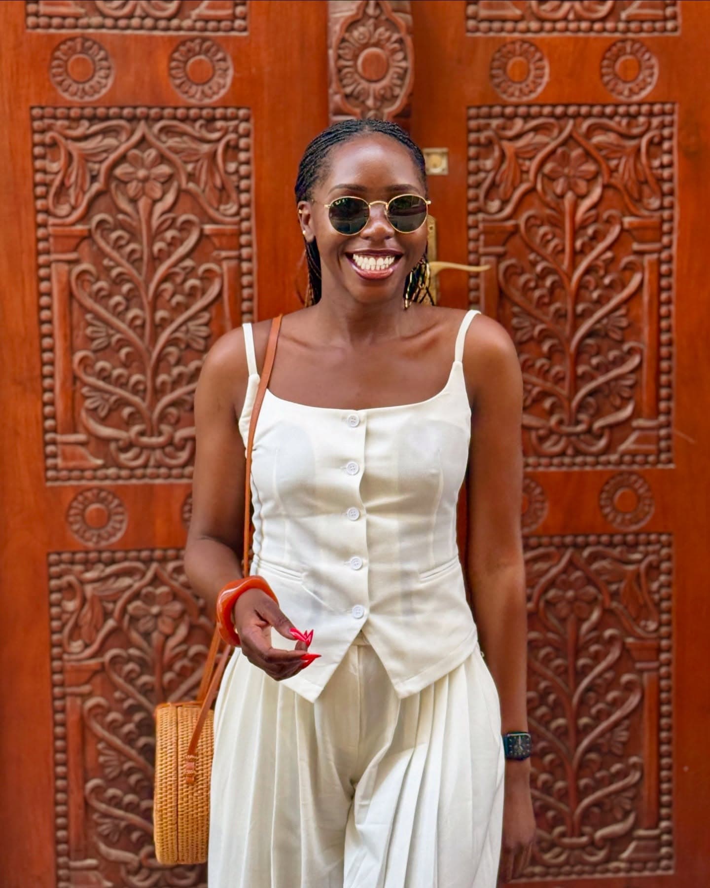 White linen outfit in front of ornate wooden door